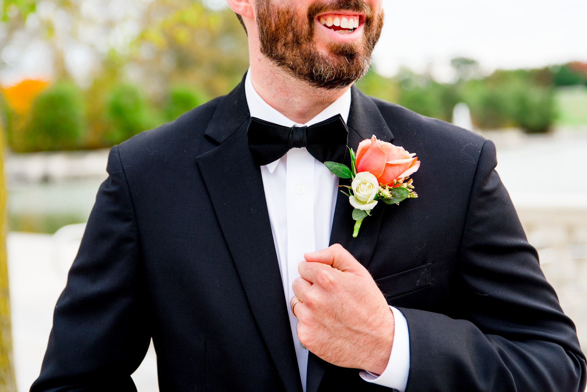 groom's smile and bowtie with coral rose boutonniere showing for St. Louis fall wedding portraits for Chicago couples