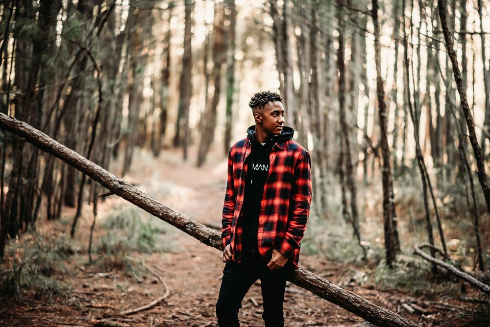 High School Senior Photo of a boy standing in the woods wearing buffalo plaid