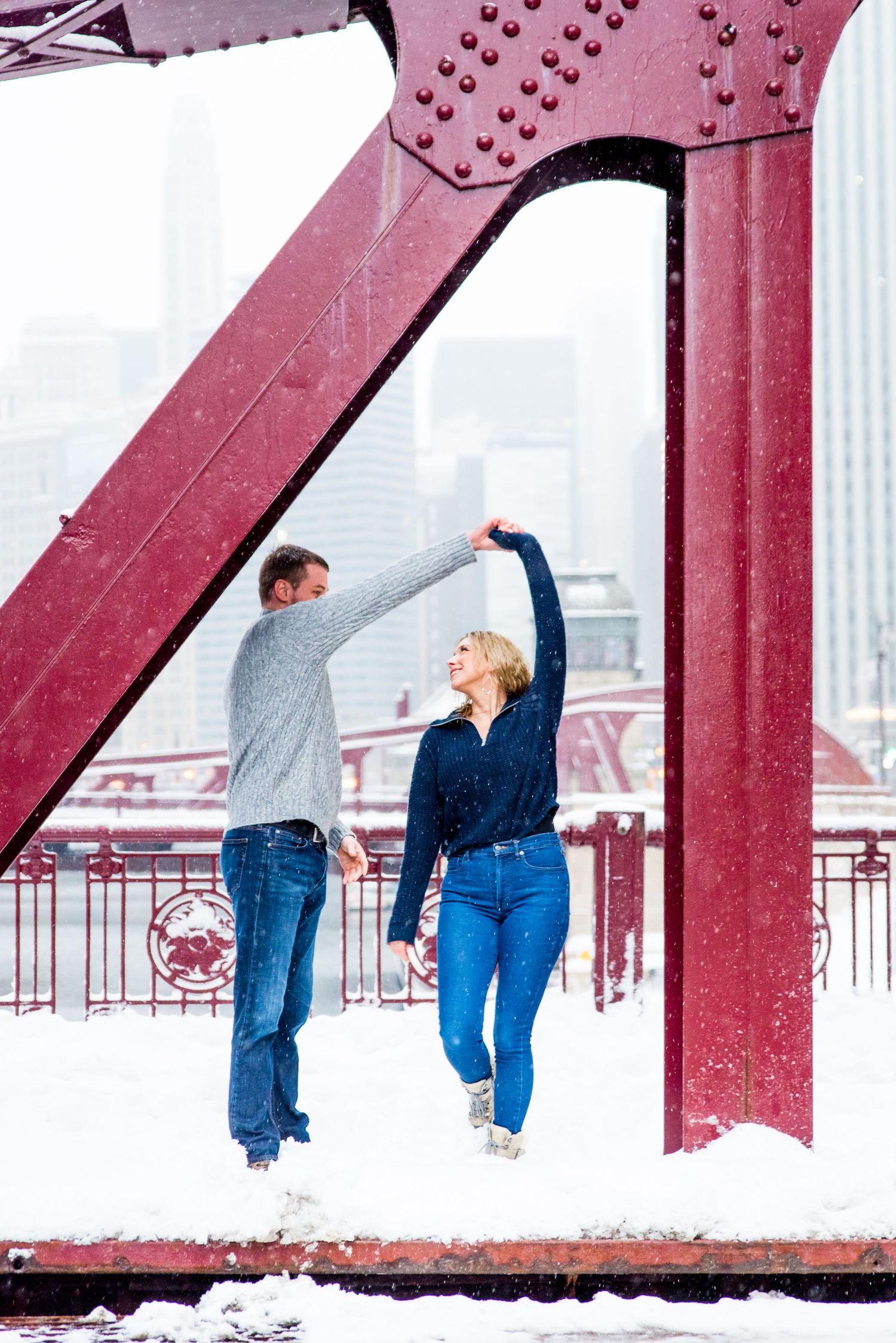 young couple hugging under bridge for Chicago urban engagement pictures in the snow