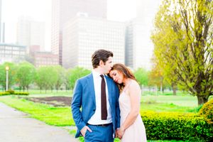 man in Navy suit kissing fiancee in pink dress on forehead in Chicago Grant Park for sunset engagement pictures