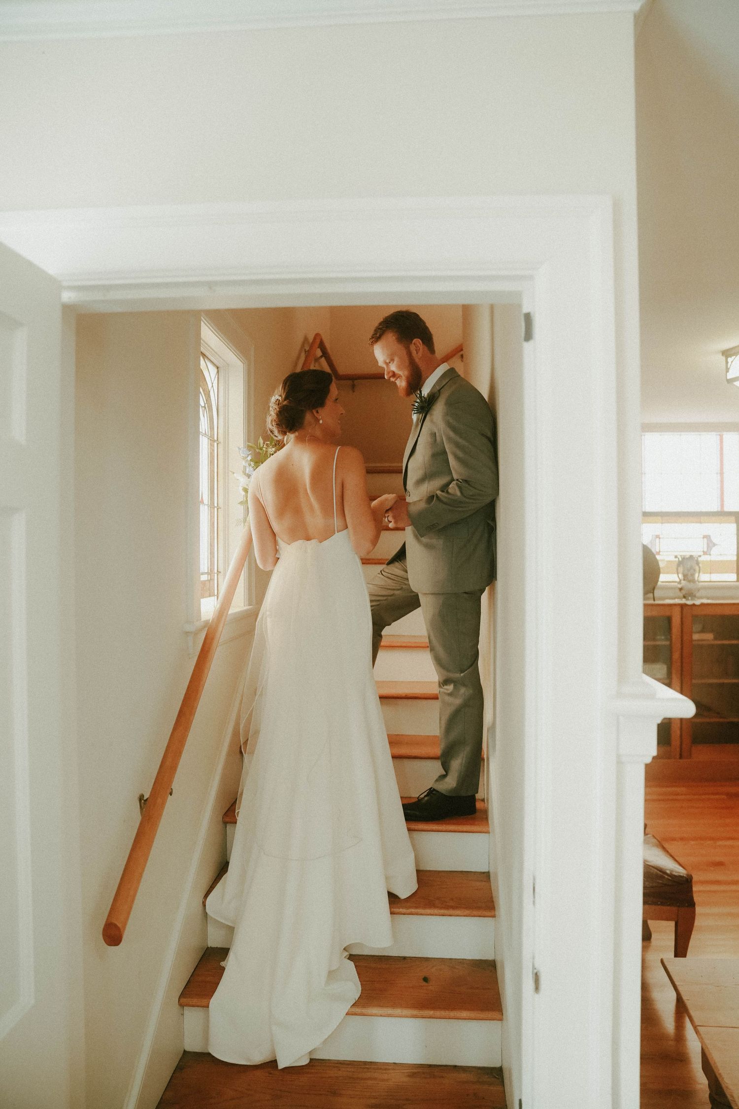 Wedding couple on wooden staircase in white dress and grey suit.