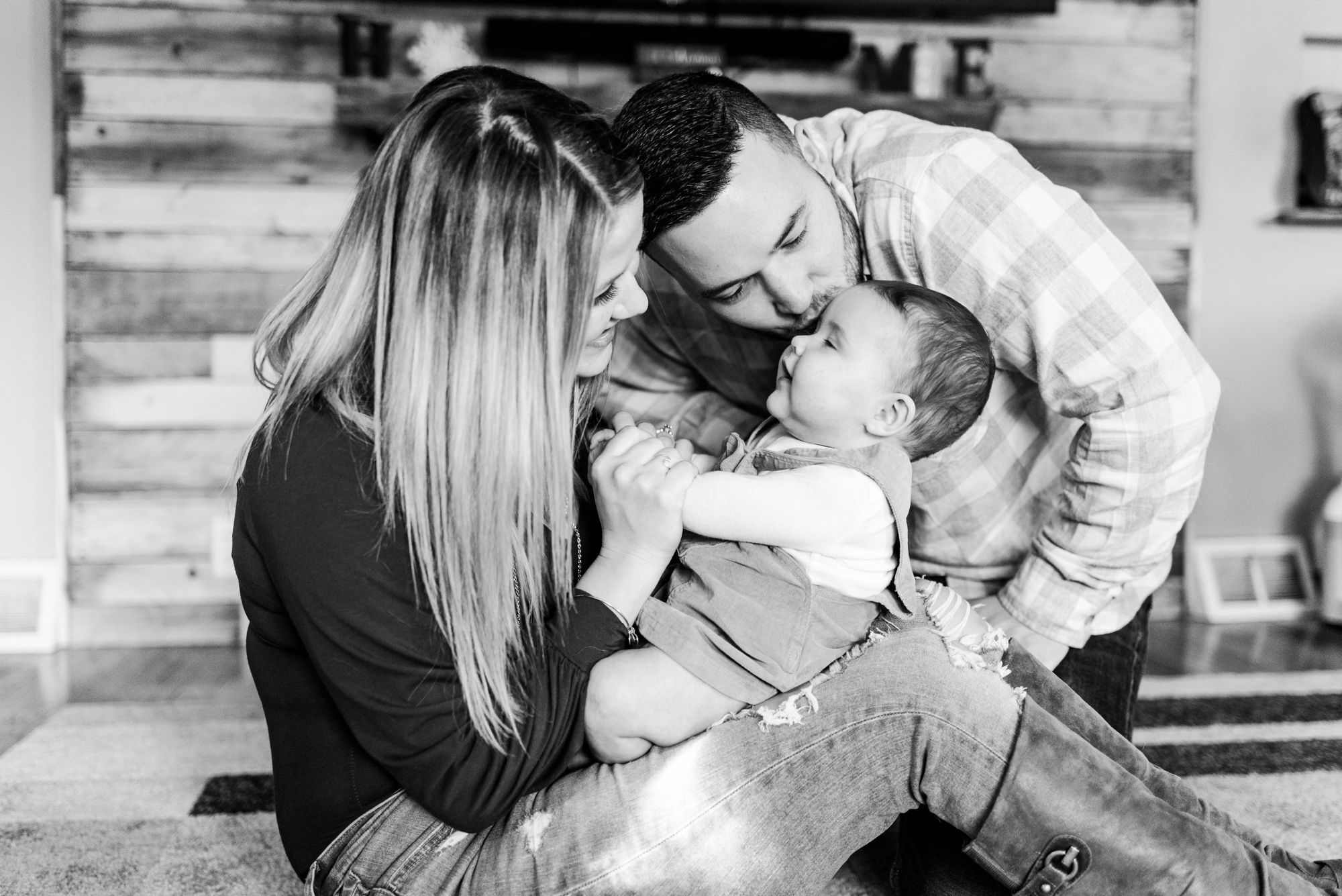 Lifestyle family photoshoot in the home with mom and dad kissing 6 month old baby in Gibsonia, Pennsylvania