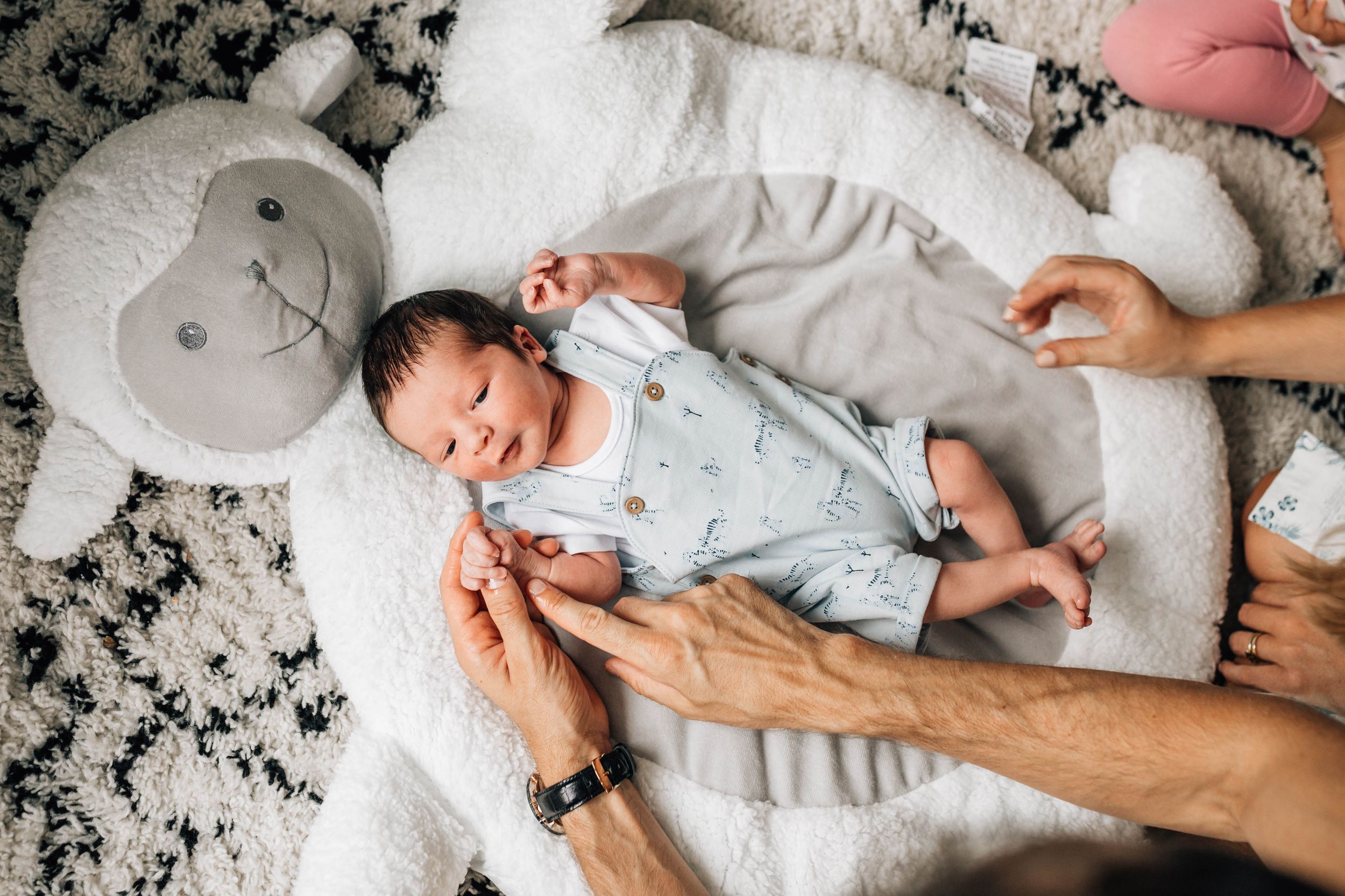 newborn baby boy laying on big white fluffy pillow on floor