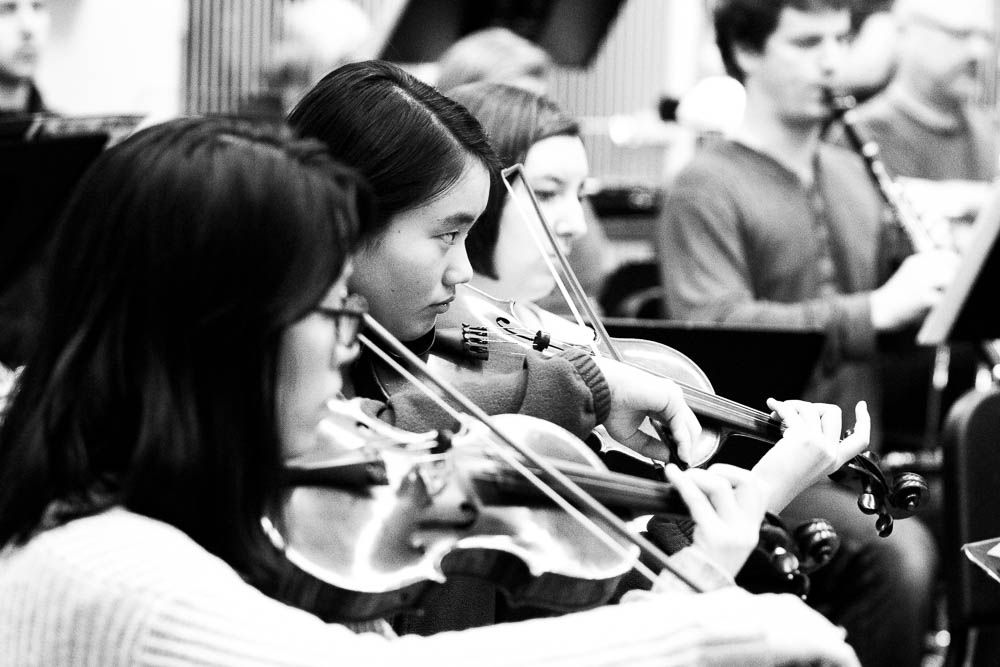 Young musicians of the Seattle Collaborative Orchestra focus intently during rehearsal.
