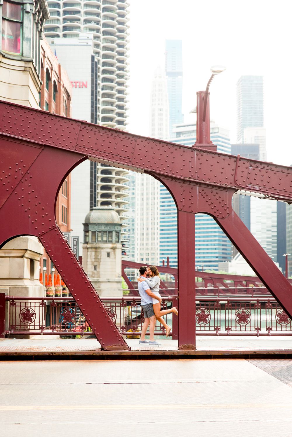 man picking up woman and kissing her on LaSalle Street Bridge for Chicago engagement pictures at sunrise
