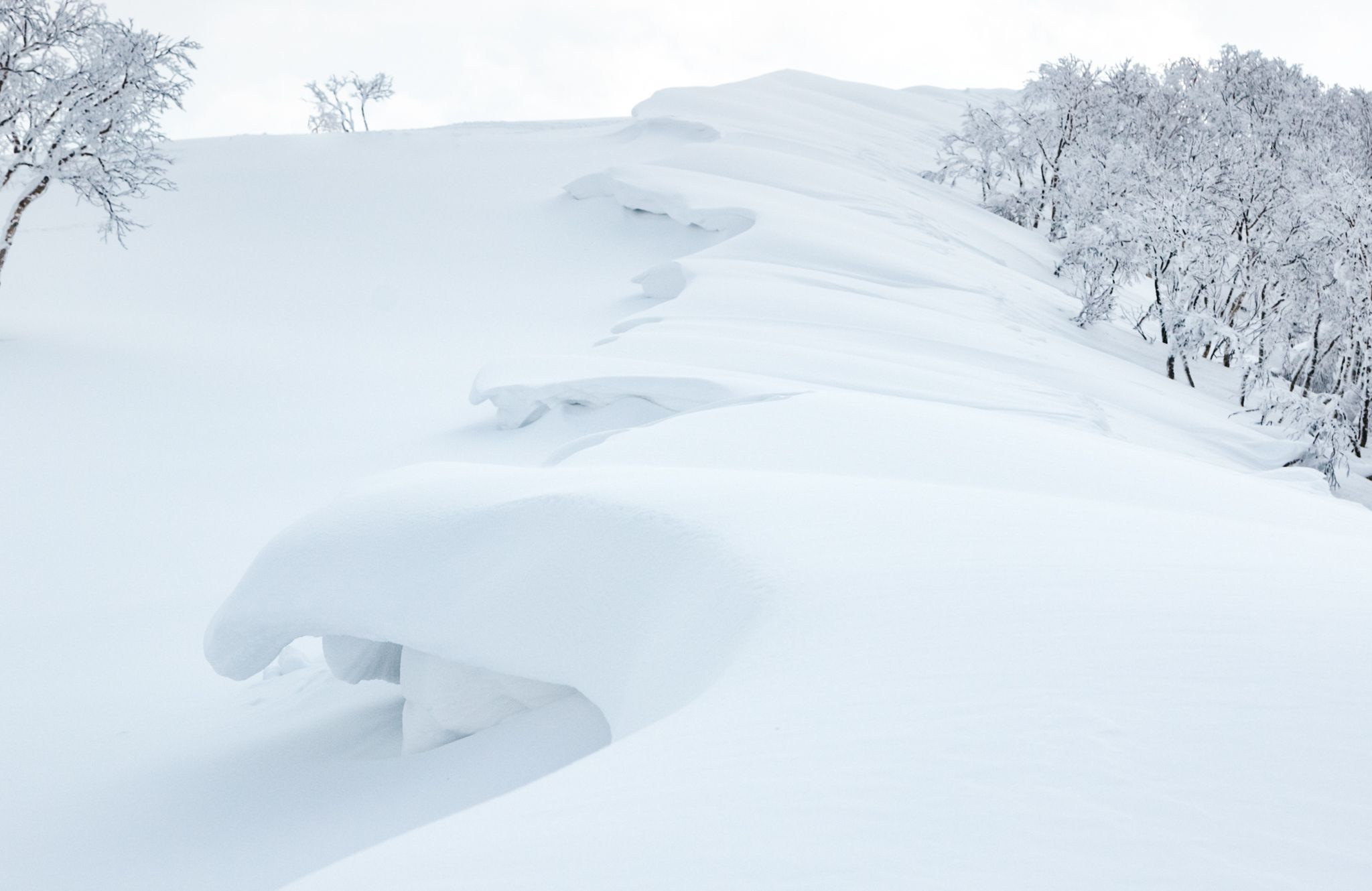 Huge wind lip cornice on a mountain top. Wind formed snow and ice sculpture