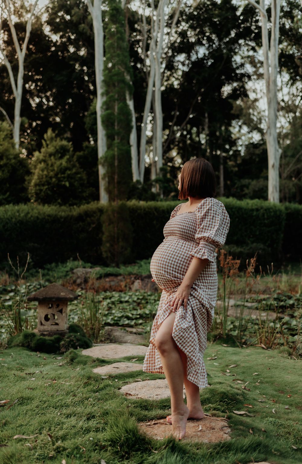 pregnant mum holding belly and looking out to botanical gardens