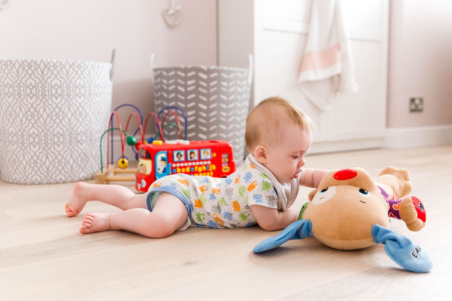 baby girl laying on belly on floor playing with soft plush toy
