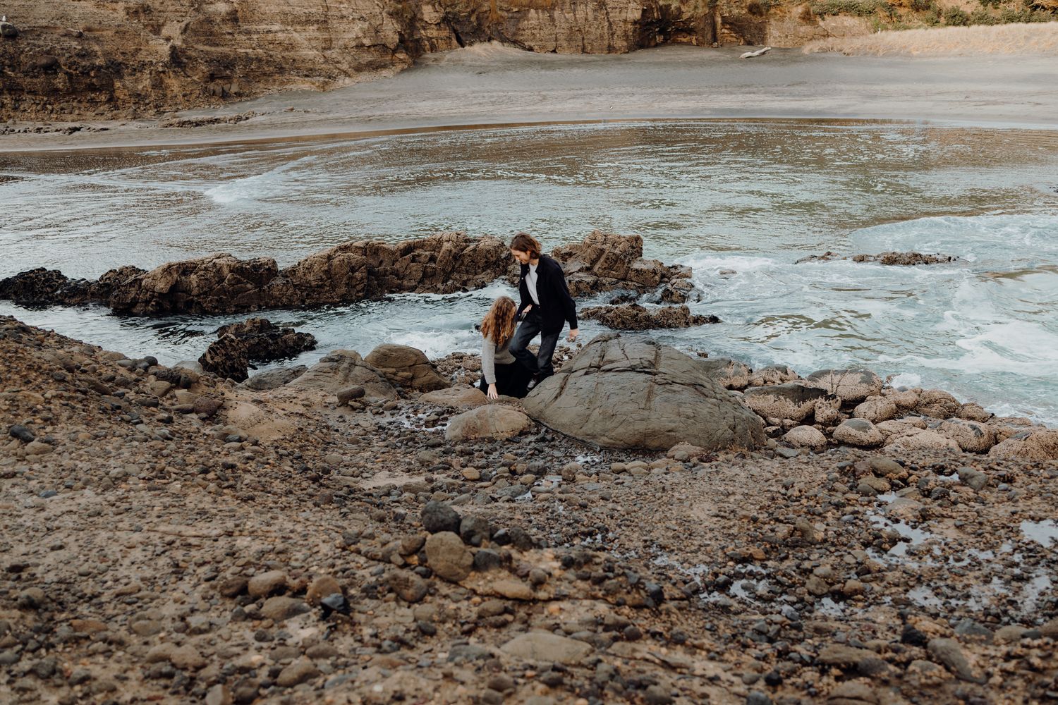 A couple hiking the cliff in Piha for their engagement with Apertured Media-Auckland Wedding and Elopement Photographer