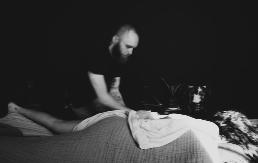 A massage therapy giving a massage to a person lying face down in black-and-white with the therapist in blur