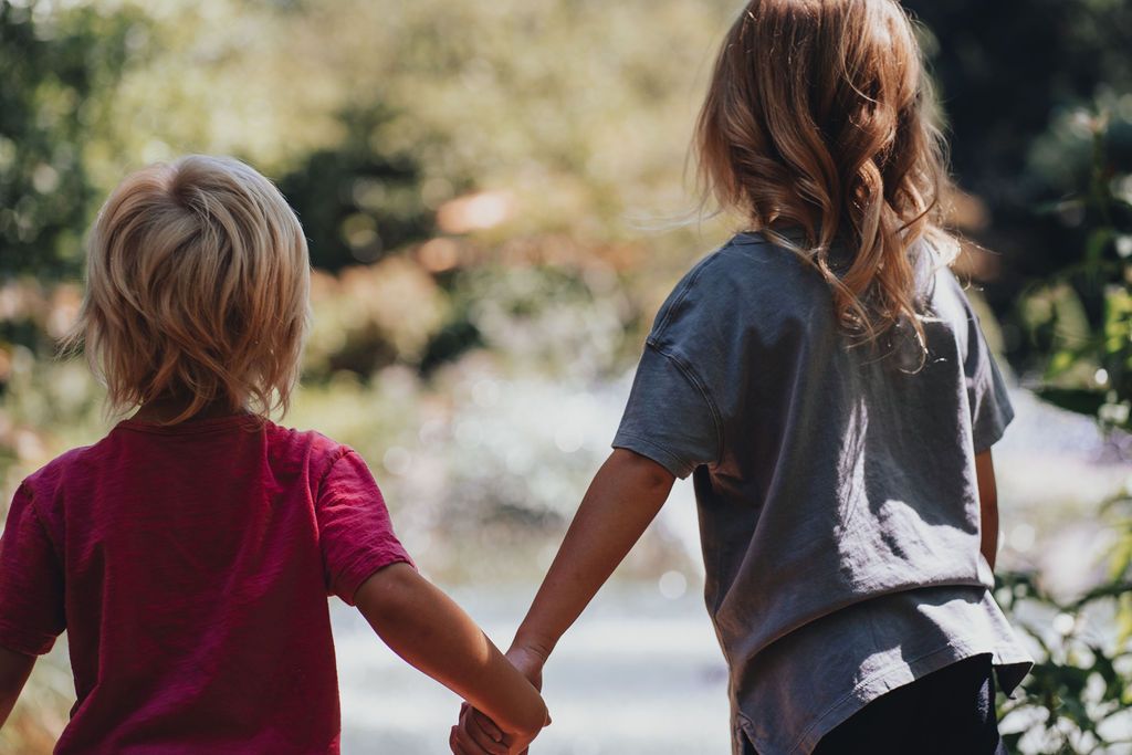 Brother and sister (grandkids) hold hands while watching the fountain in the pond at Sayen Gardens, also spotting coy.