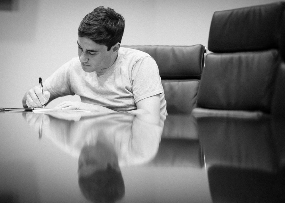 Groom Write Vows at Conference Room Table with reflection from table