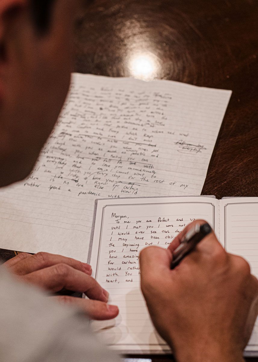 Close up of man's hands and letter as he writes his wedding vows.