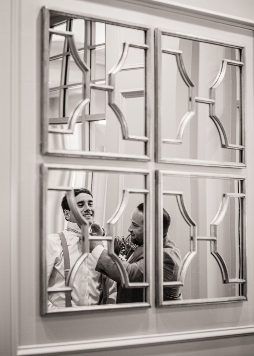 reflection of groom getting help with his tie at the stone briar country club in frisco Texas