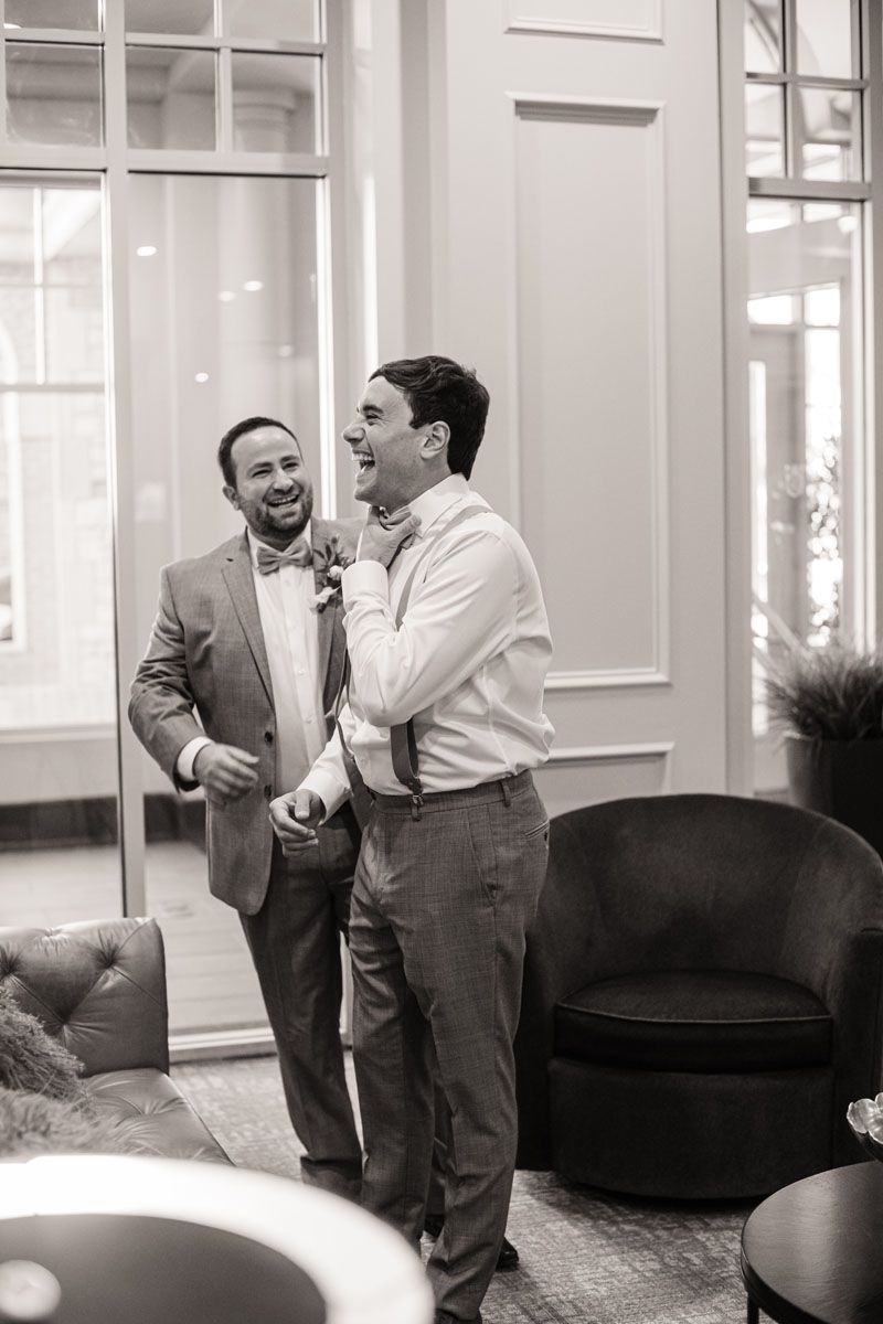 Groom laughs with his best man has he gets help with this tie at Stone Briar Country Club