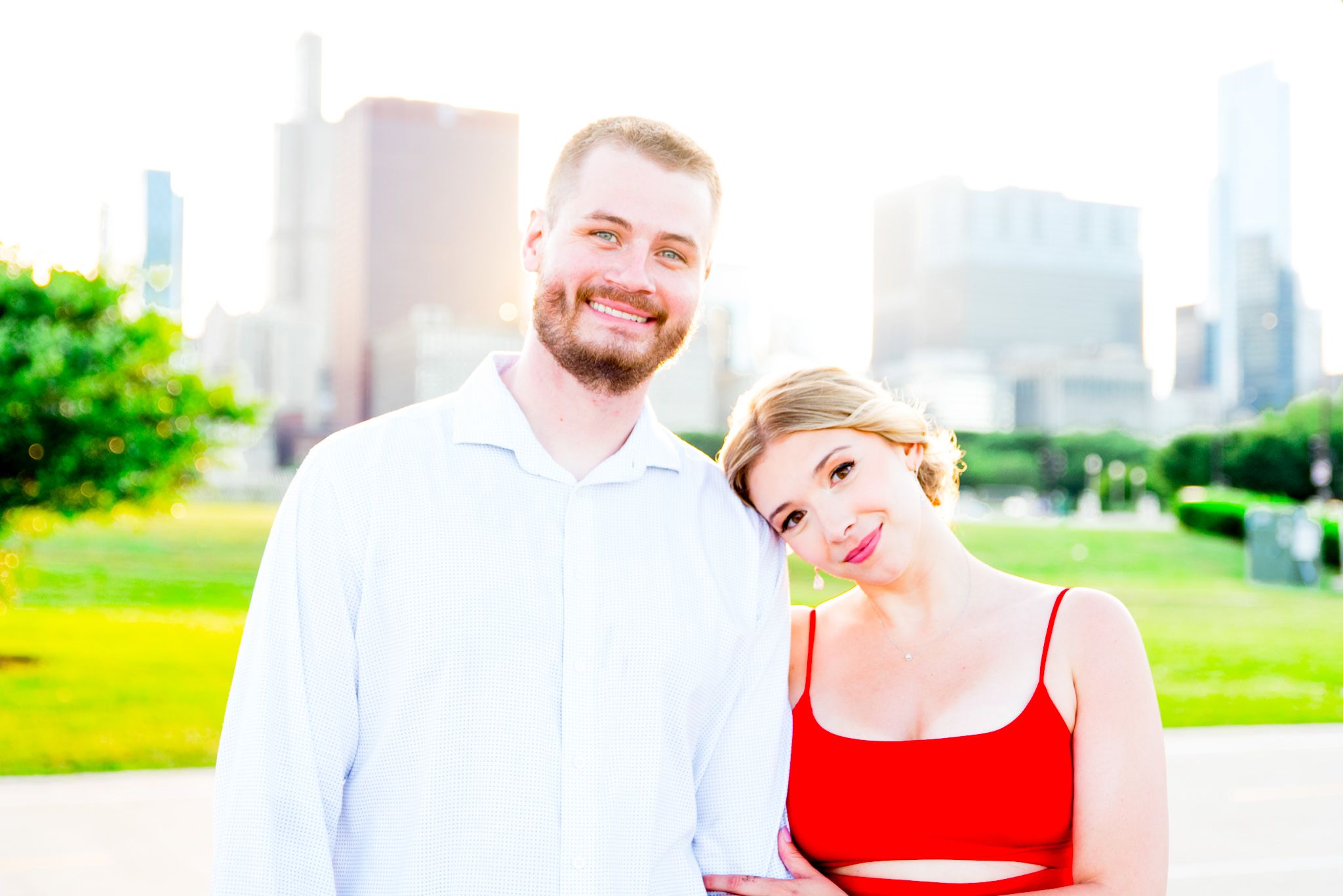 woman in red dress leaning on fiance's shoulder at Grant Park in Chicago at sunset