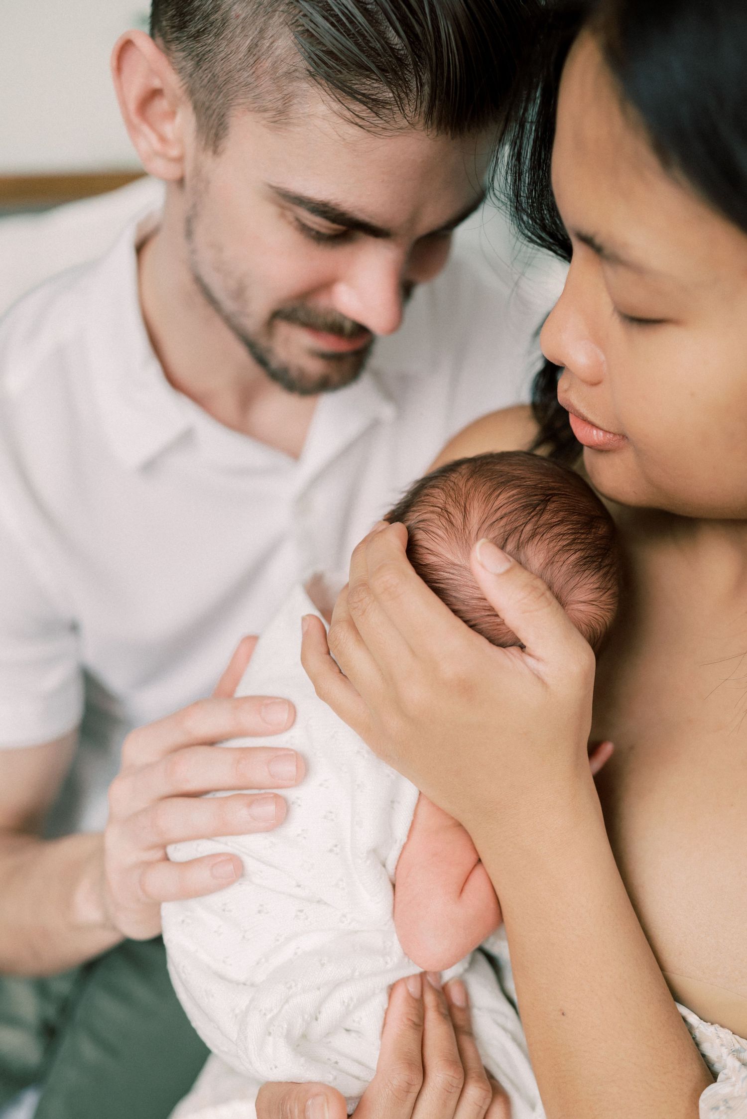 A tender family moment with a newborn baby wrapped in white.