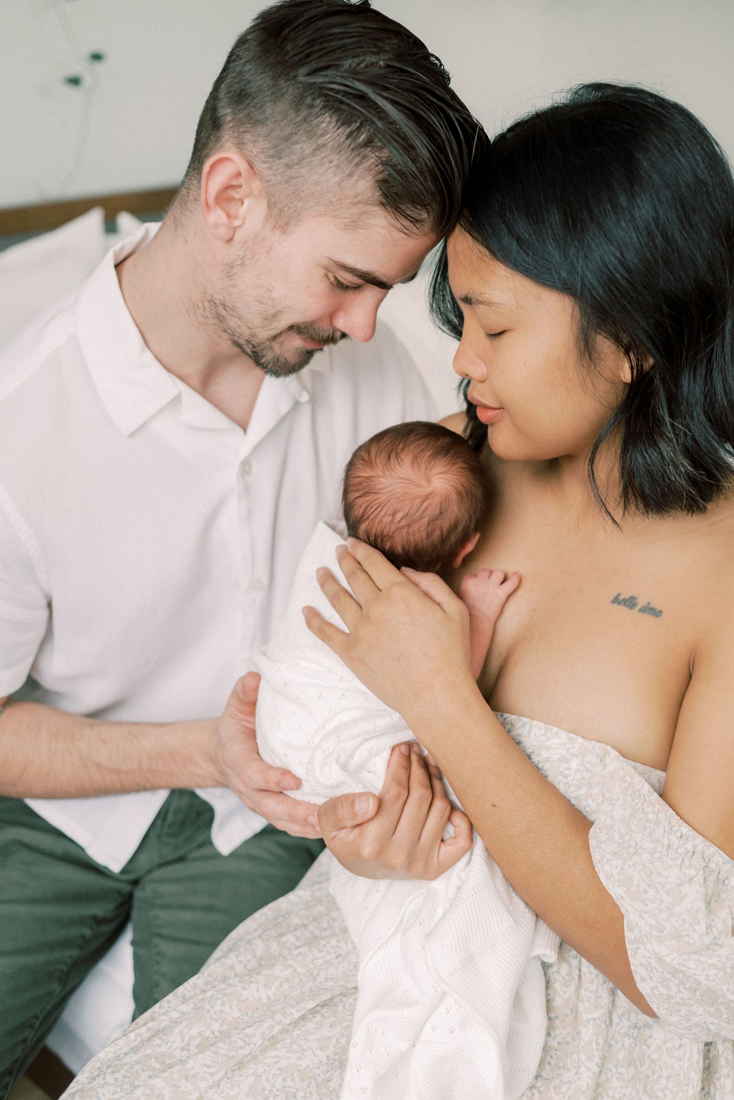 An intimate family portrait with a newborn baby in soft natural lighting.