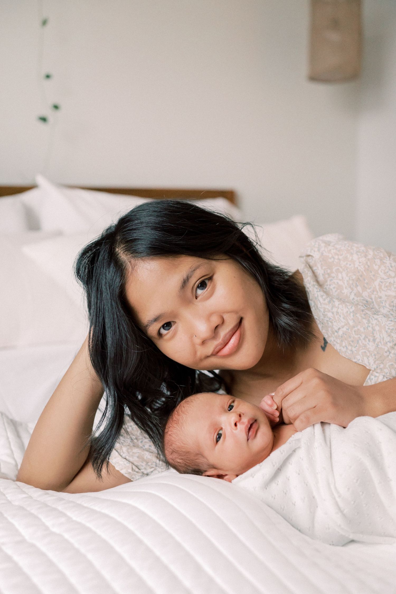 A sweet moment captured between parent and baby on white bedding.