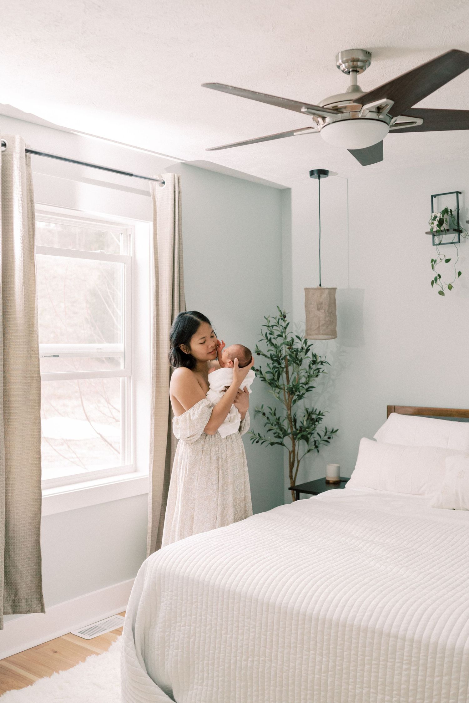 A serene bedroom scene with soft natural light, white bedding, and gentle sage green walls.