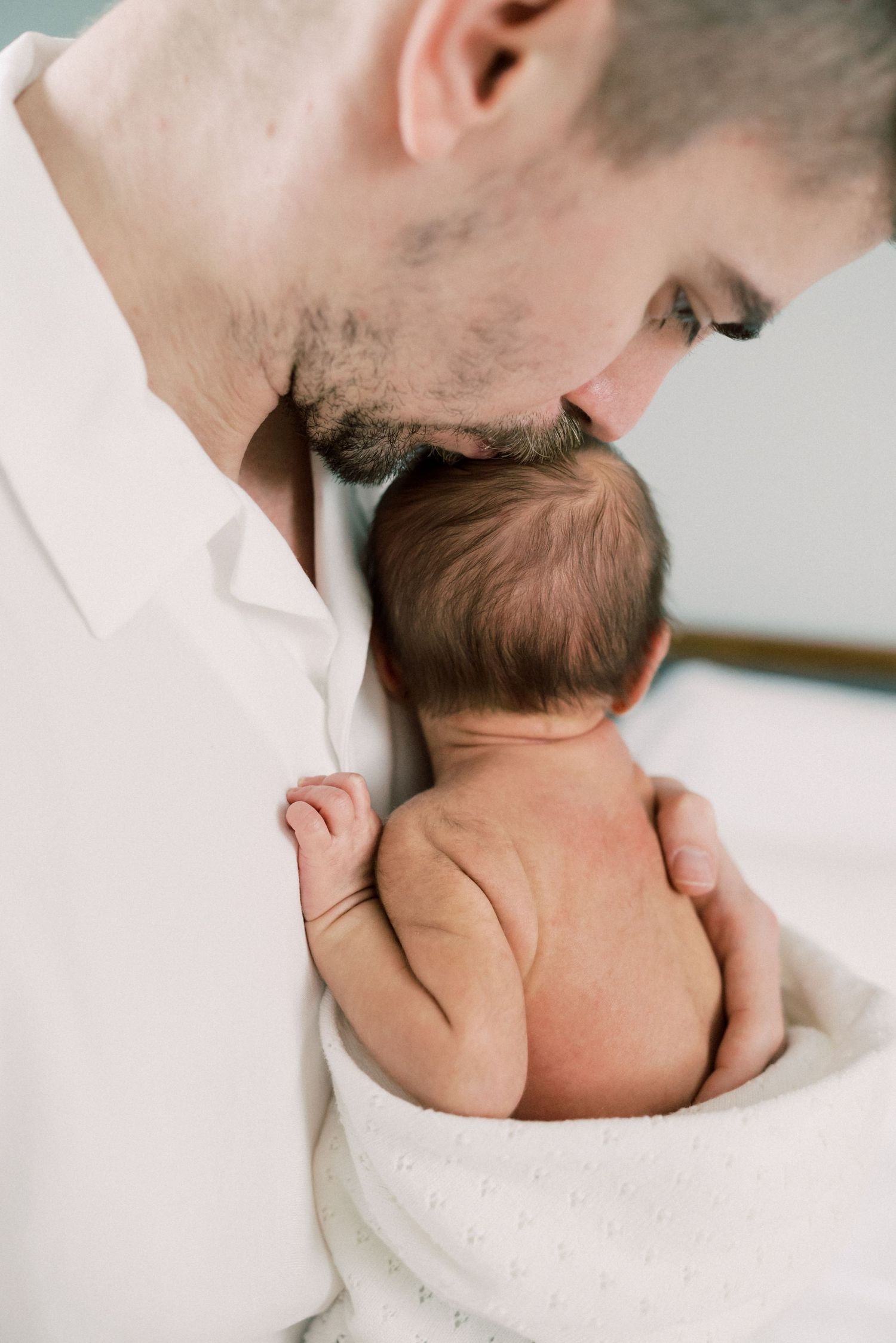 A tender moment with a newborn baby wrapped in a white towel.