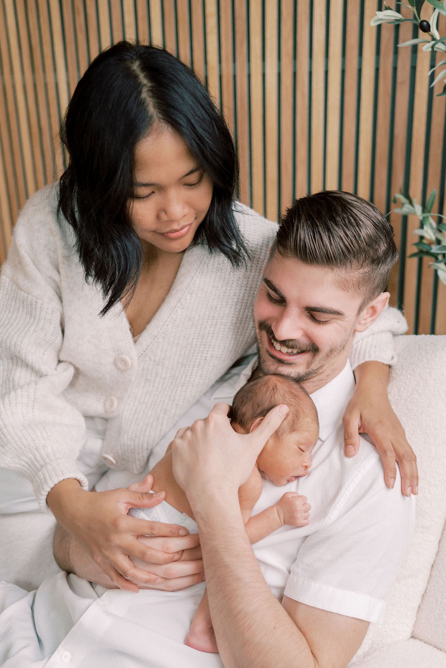 A cozy family moment beside wooden slat walls with indoor plants.