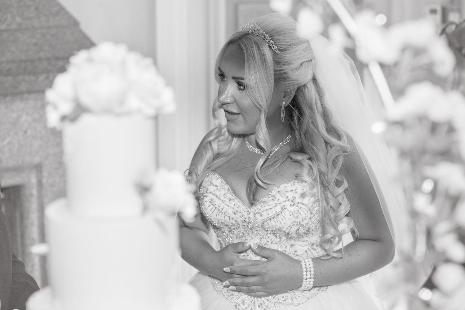 Black and white image of Bride with cake in soft focus in foreground