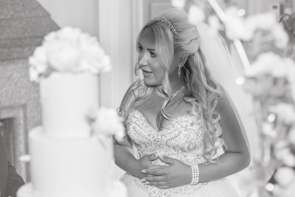 Black and white image of Bride with cake in soft focus in foreground