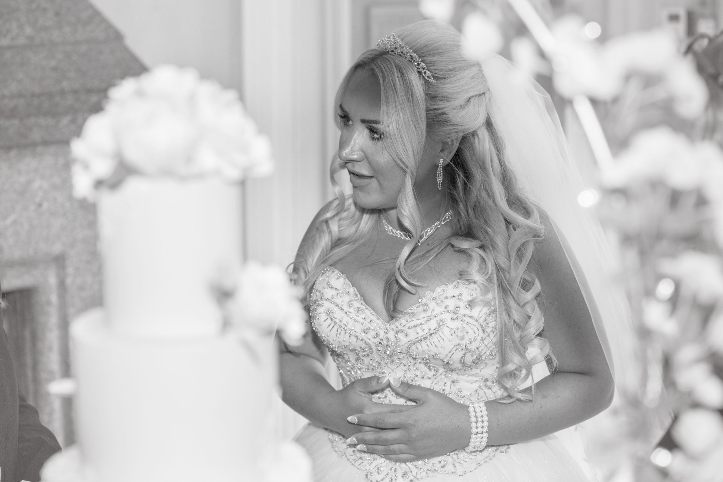 Black and white image of Bride with cake in soft focus in foreground