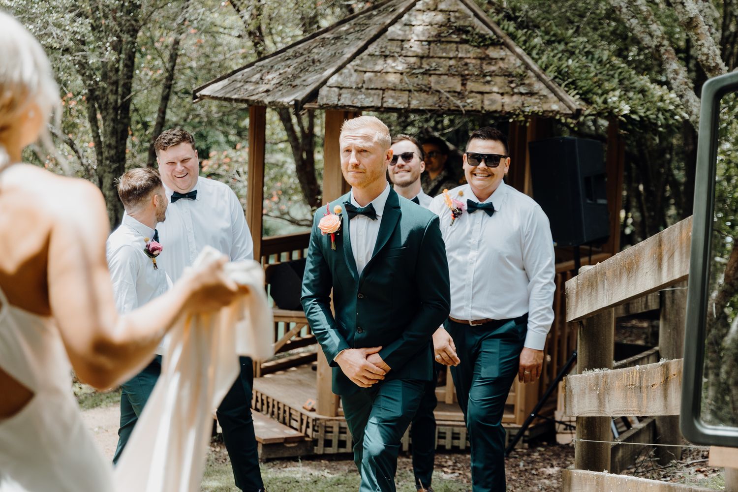 Wedding ceremony moment captured at a rustic outdoor gazebo surrounded by greenery.