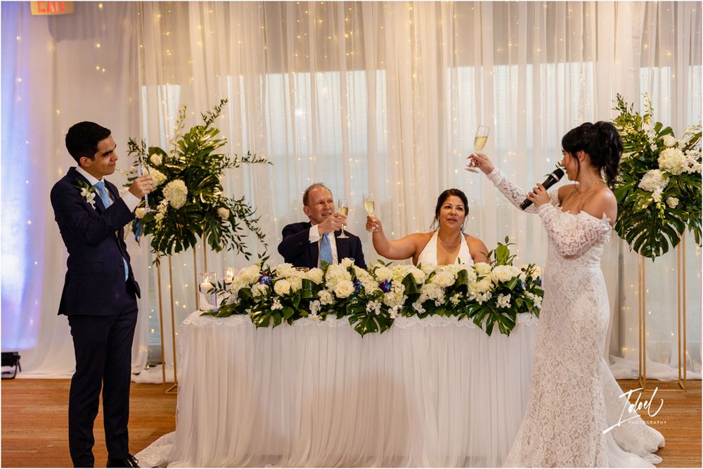 Wedding reception celebration with toasts and cheers at the head table.
