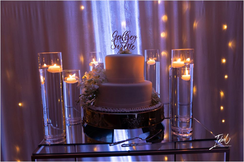 Wedding cake display with glowing candles and romantic uplighting creating an elegant atmosphere.