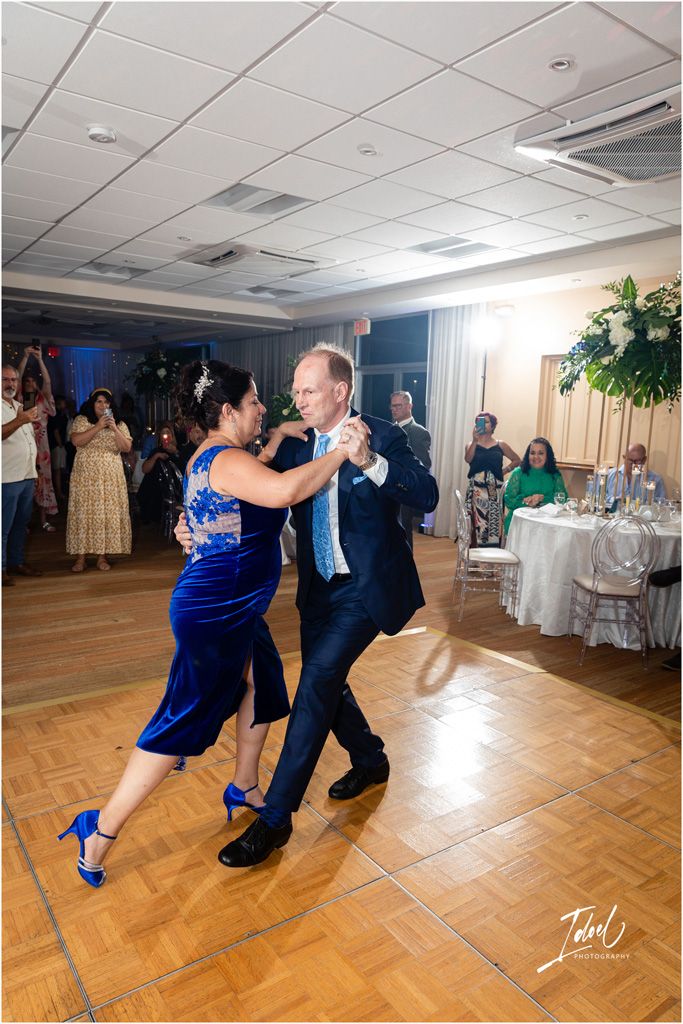 Lively dancing at a wedding reception with elegant table settings in the background.