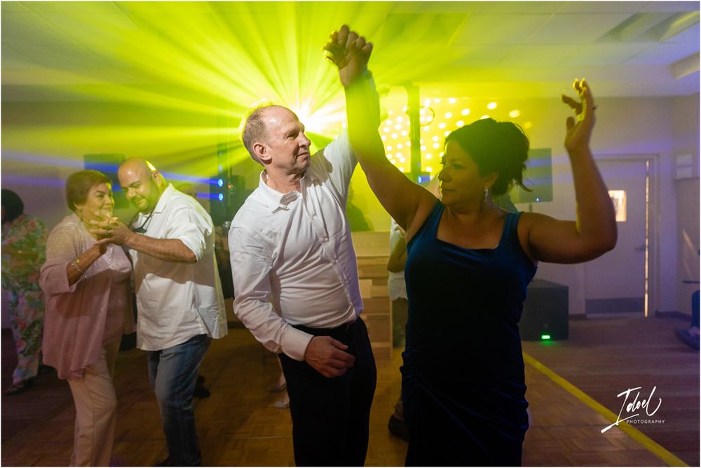 Energetic dancing at wedding reception with vibrant yellow lighting effects.
