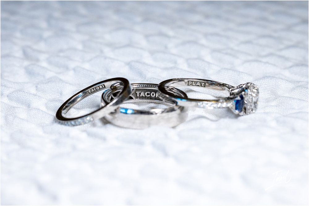Three wedding rings photographed on white textured surface with blue accent stone.