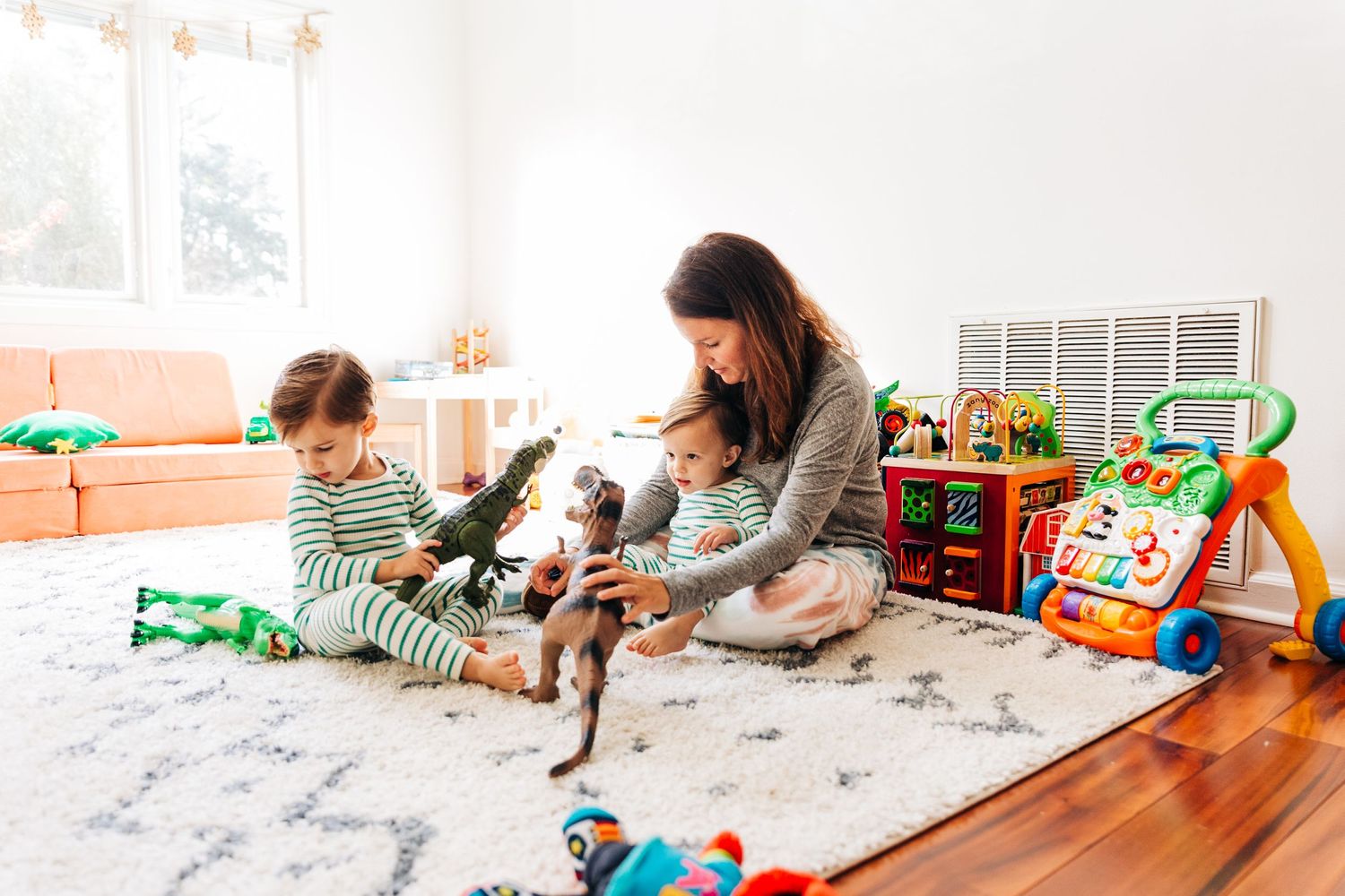 A mom playing with her two young sons on their playroom floor