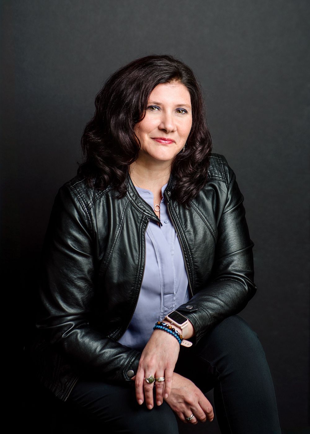 Professional studio portrait with black leather jacket against dark background.
