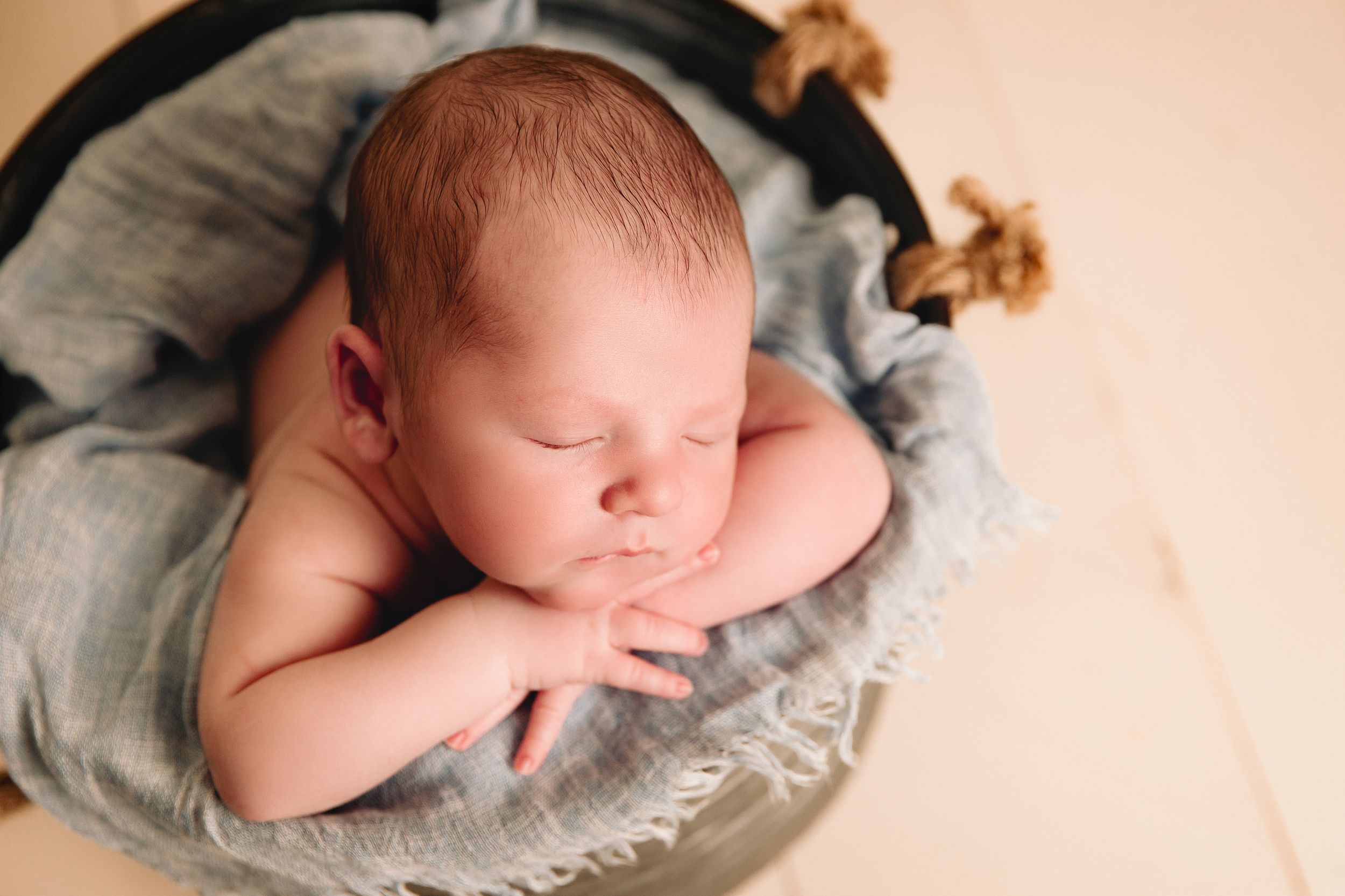 close up of infant in a newborn photography prop bucket