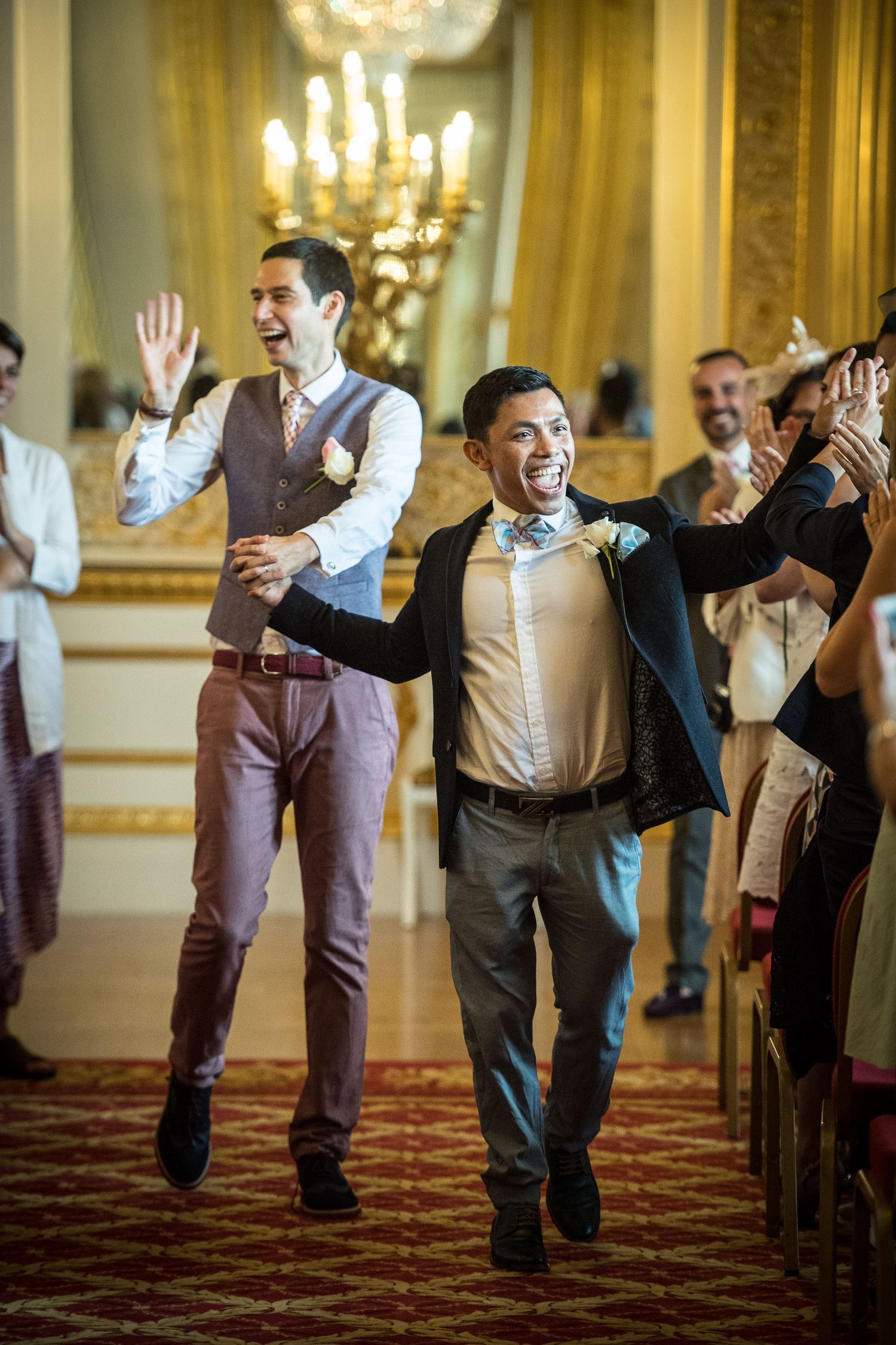 two grooms high five their guest as they walk down the aisle together after their Lancaster house gay wedding ceremony
