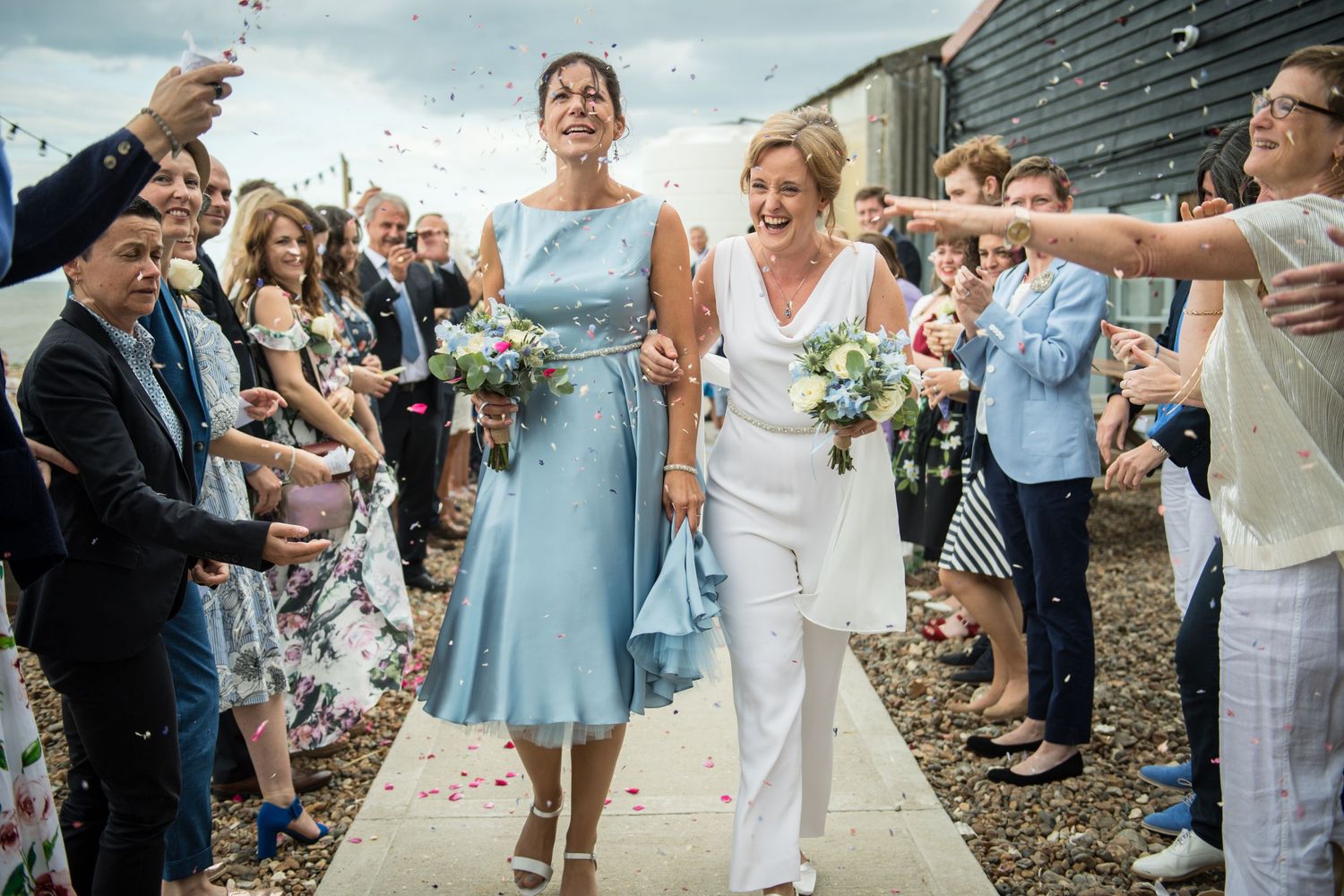 two brides are showered with confetti on a whitstable beach