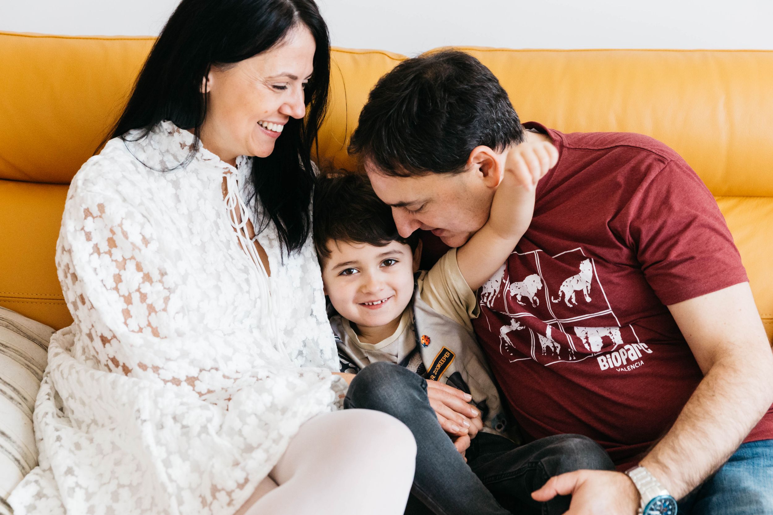 family of three portrait on yellow sofa