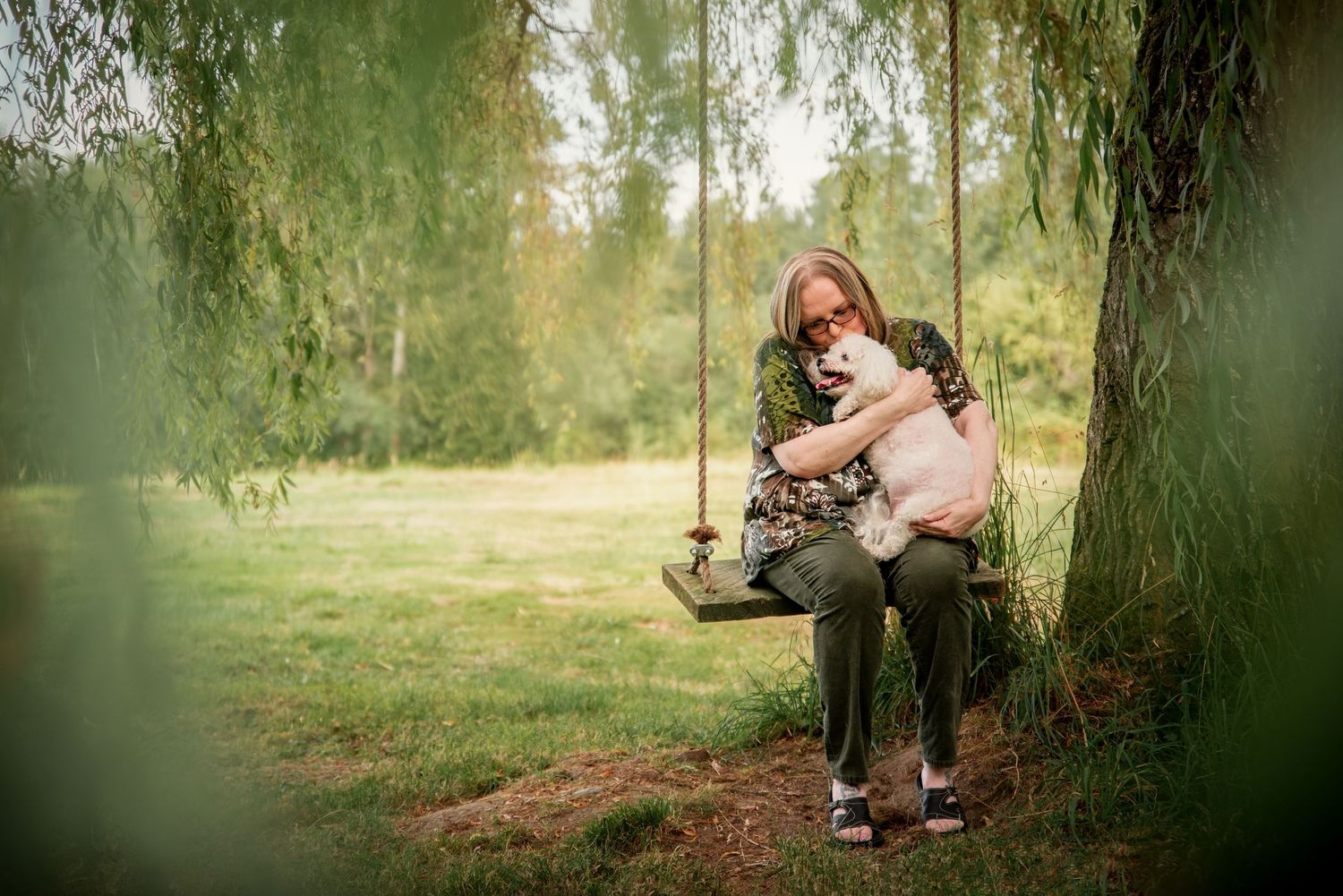 Woman on a rope swing holding senior dog for a portrait session in Tacoma