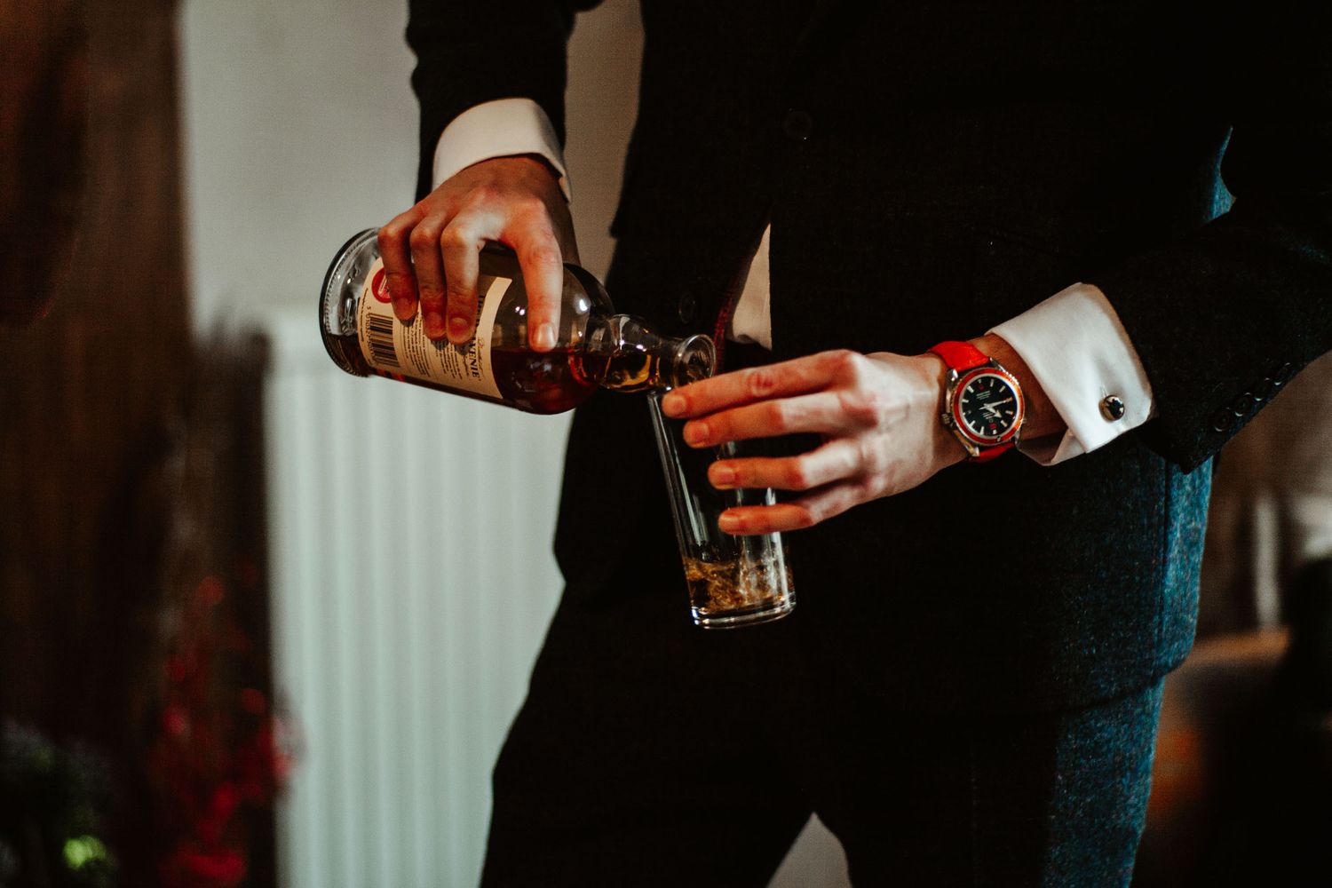 Groomsman pours a glass of whiskey in the morning