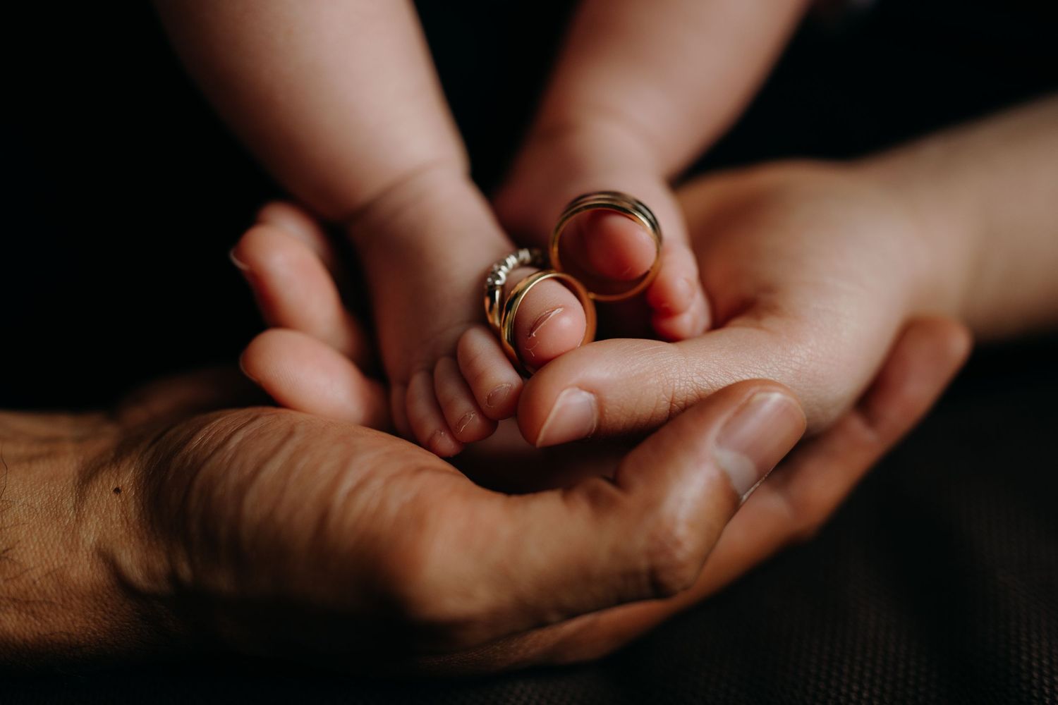newborn feet with parents holding hands rings balance on toes