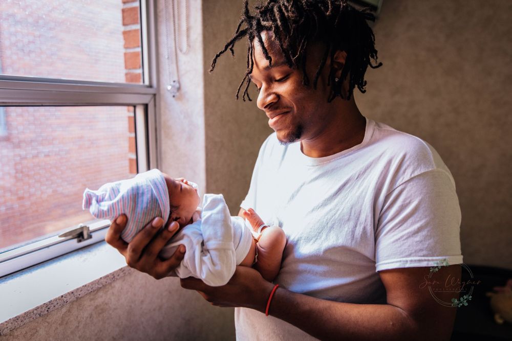 Birth photographer captures proud Arkansas father as he holds newborn baby in hospital