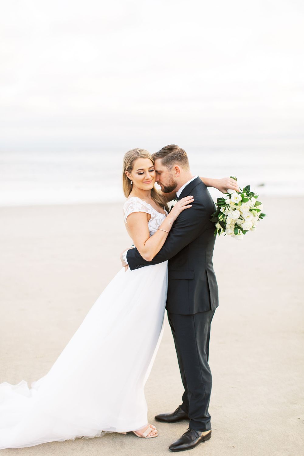 bride and groom getting close on the beach during couples portraits at the westin resort in hilton head island, sc