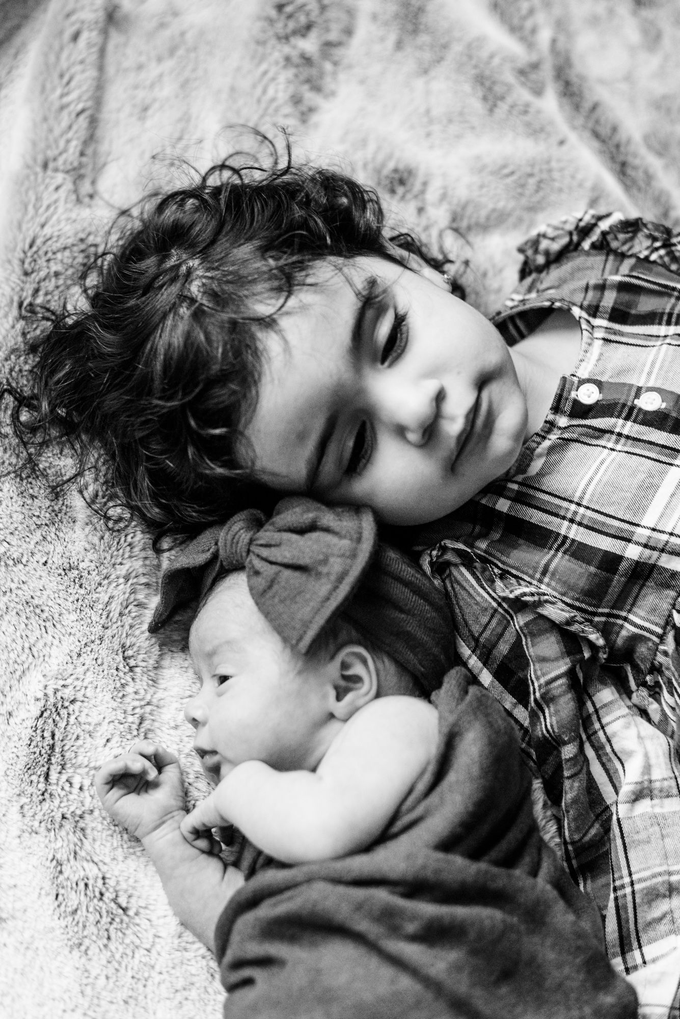 Lifestyle newborn black and white with bow with big sister in Pittsburgh, Pennsylvania