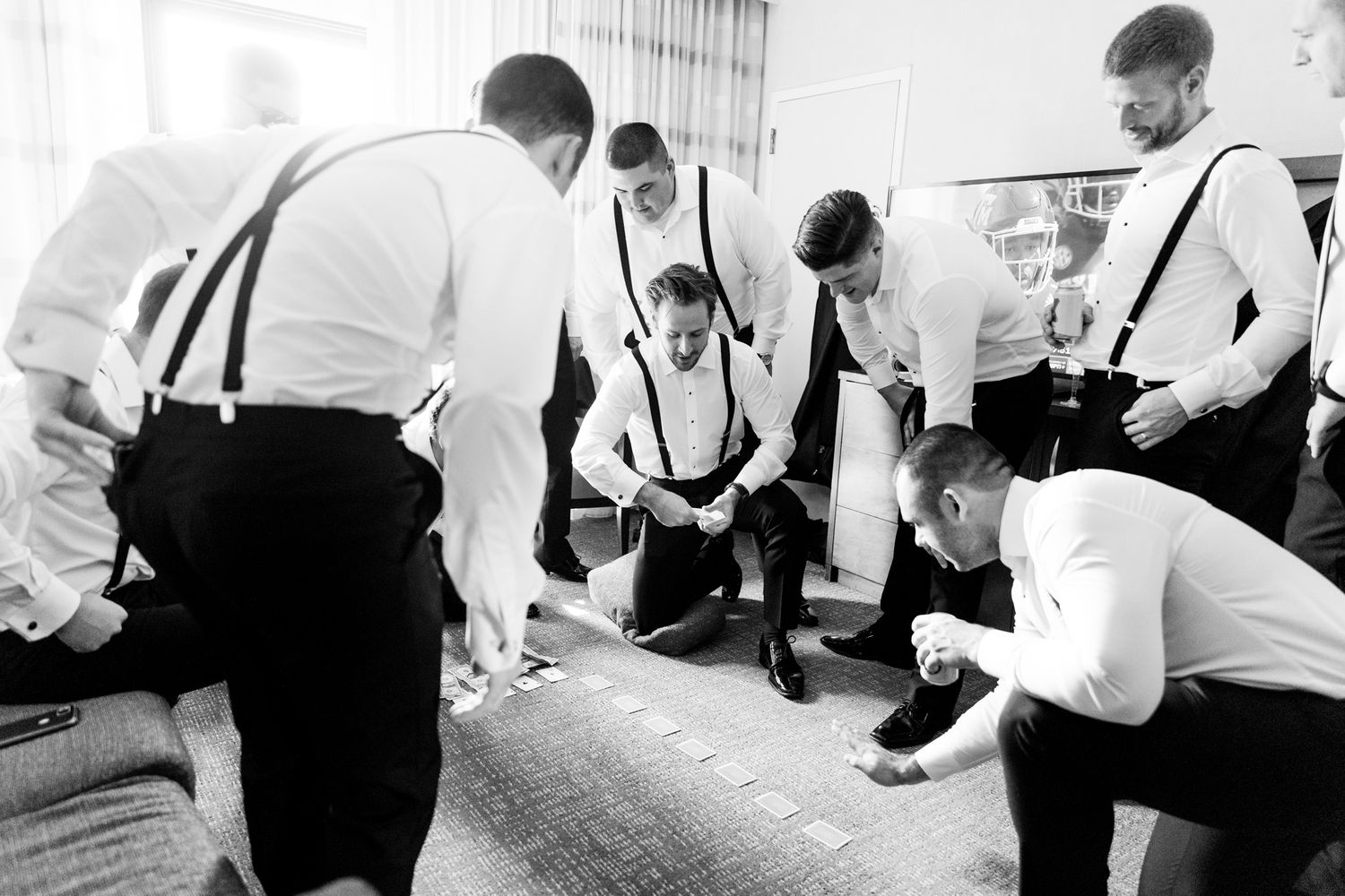 group of groomsmen play card games in chicago hotel before wedding ceremony