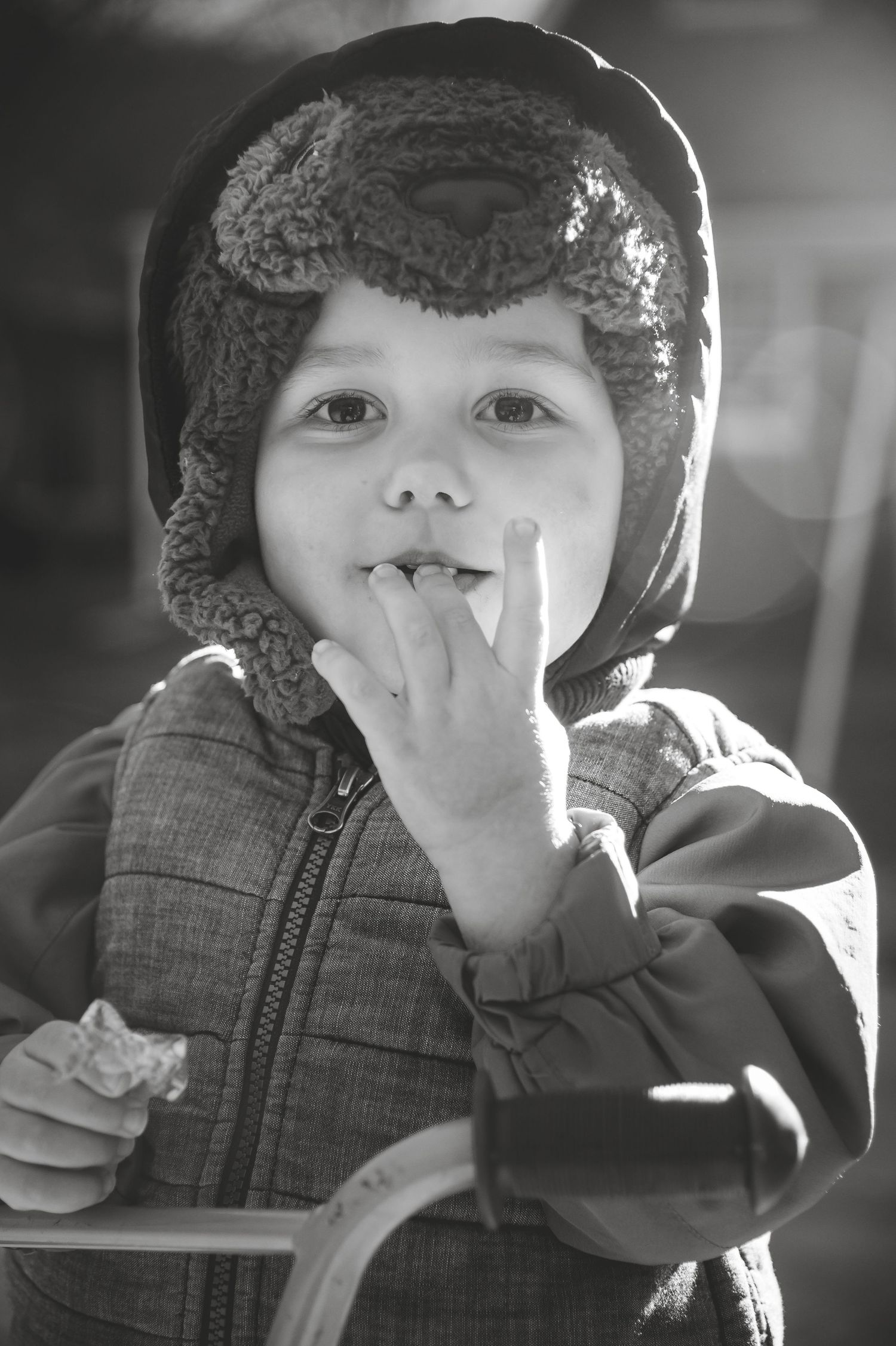 boy eating candy while looking at camera wearing hat and winter jacket while riding bike with flash illuminating behind