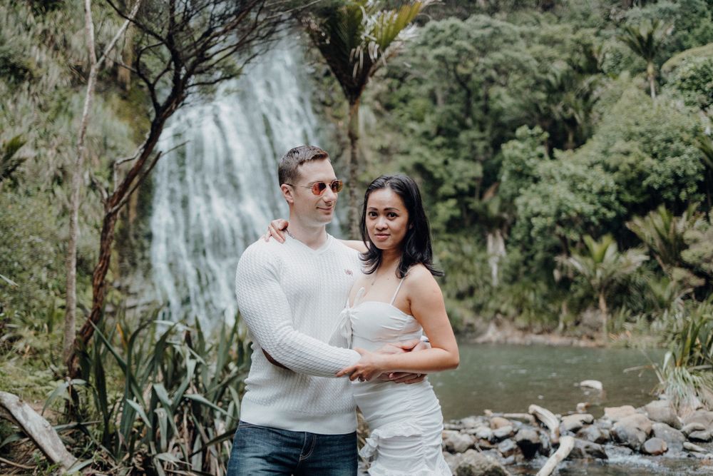 A couple shares an intimate moment against the backdrop of a tropical waterfall setting.